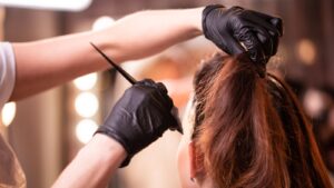 Peluquera profesional aplicando tinte con brocha a una clienta en el salón