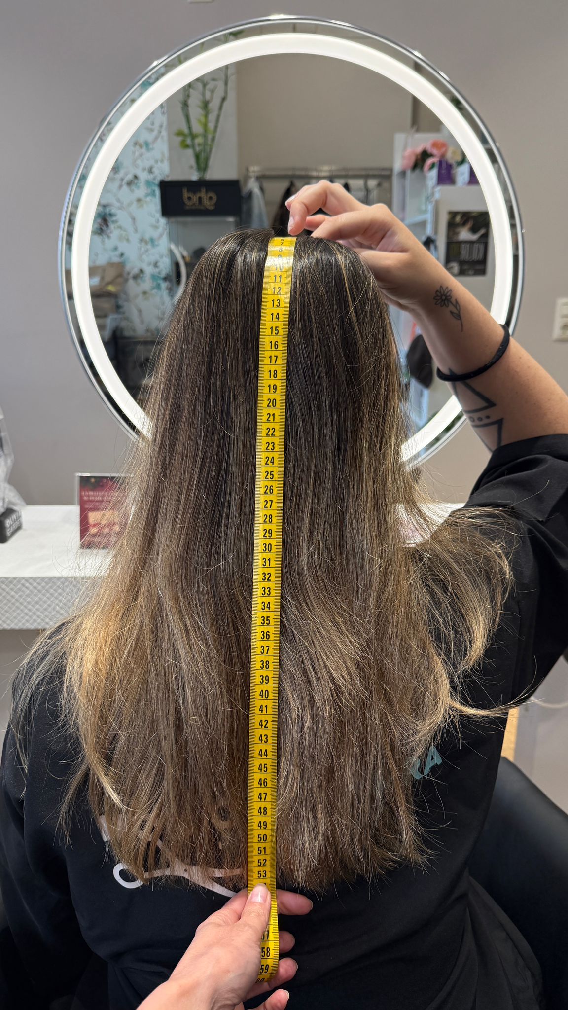 Medición del largo total del cabello con cinta métrica en un salón de peluquería